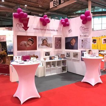 Mama Moments Stand mit vielen Neugeborenen und Babybauch Shooting Bildern.